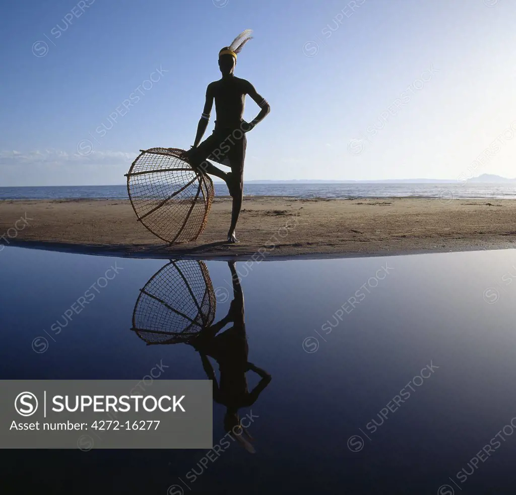 A lone Turkana fisherman with his traditional fishing basket strikes an impressive pose on the shores of Lake Turkana as he waits the arrival of his companions before fishing the shallow waters for tilapia.