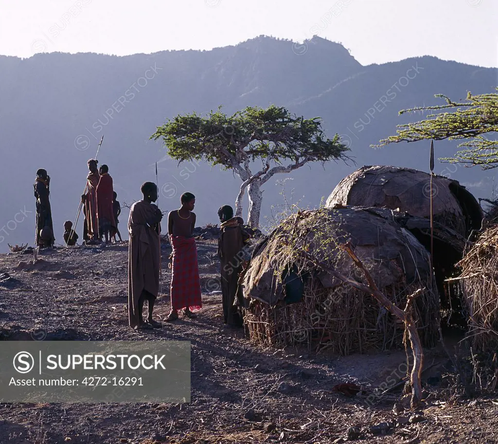 As the sun rises above the forested peaks of Mount Nyiru, members of a Turkana family chat and plan their day's activities outside their domed-shaped homes, which provide scant protection from the elements.