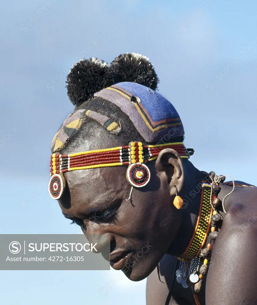 A Turkana man with a fine clay hairstyle, so typical of the southern Turkana.  The black ostrich feather pompoms denote that the man belongs to the ng'imor (black) moiety of his tribe.