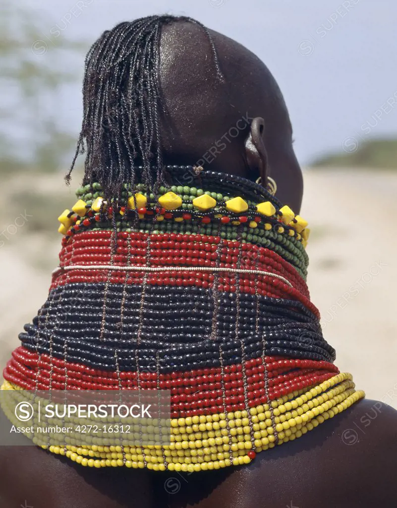 A Turkana girl's necklaces are well-oiled with animal fat and glisten in the sun.  Occasionally, a girl will put on so many necklaces that her vertebrae stretch and her neck muscles gradually weaken. The partially shaven head is typical of Turkana women and girls.