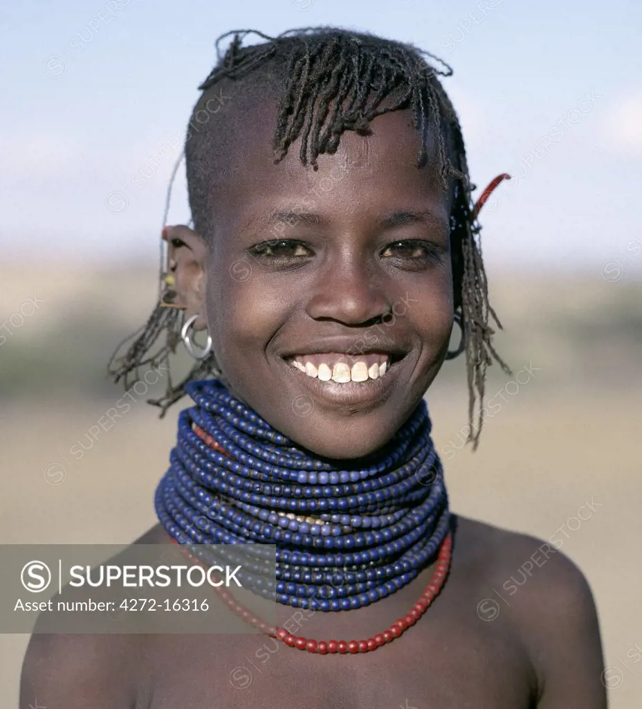 A pretty young Turkana girl has already had the flesh below her lower lip pierced in readiness for a brass ornament after her marriage. The rims of her ears have also been pierced and the holes kept open with small wooden sticks.