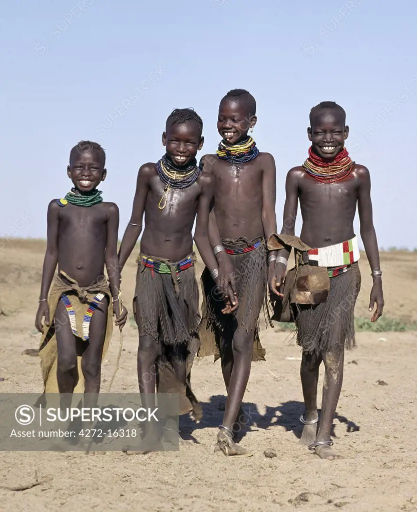 A jovial group of Turkana girls in traditional attire.  Their aprons are made of goatskin, either beaded or cut into thin strips before braiding. The two girls in the middle have already had the flesh below their lower lips pierced in readiness for a brass ornament after marriage.