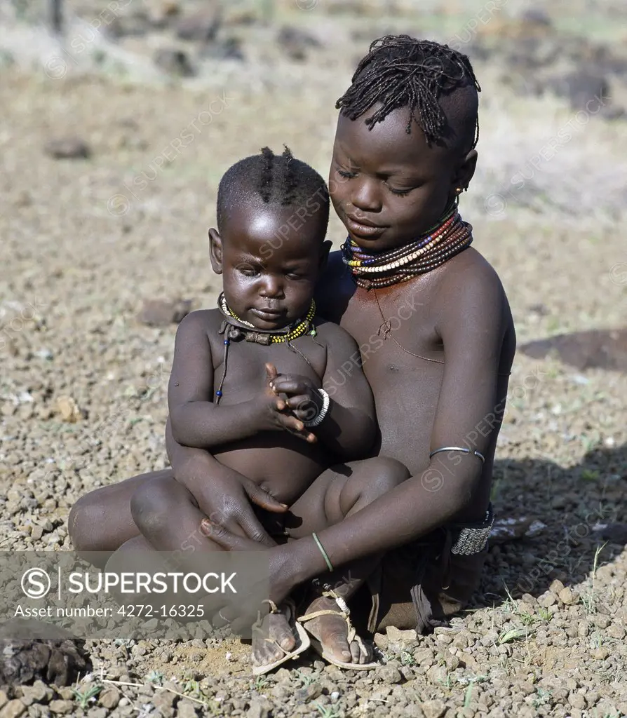 Childhood is brief in nomadic communities. From an early age, Turkana girls help their mothers with the household chores and look after their younger brothers and sisters during the day.  The baby has wooden charms round her neck to ward off evil spirits.