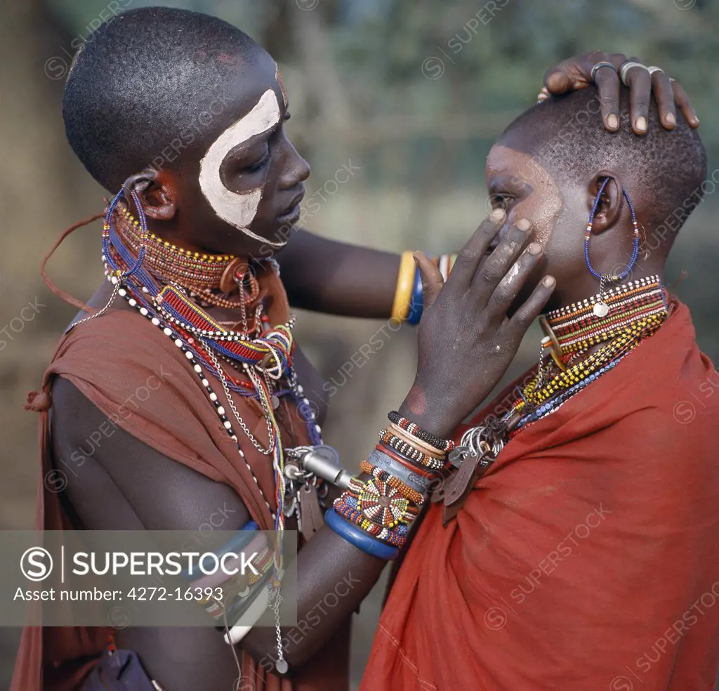 Young Maasai girls decorate their faces with ochre and clay in preparation for a dance.