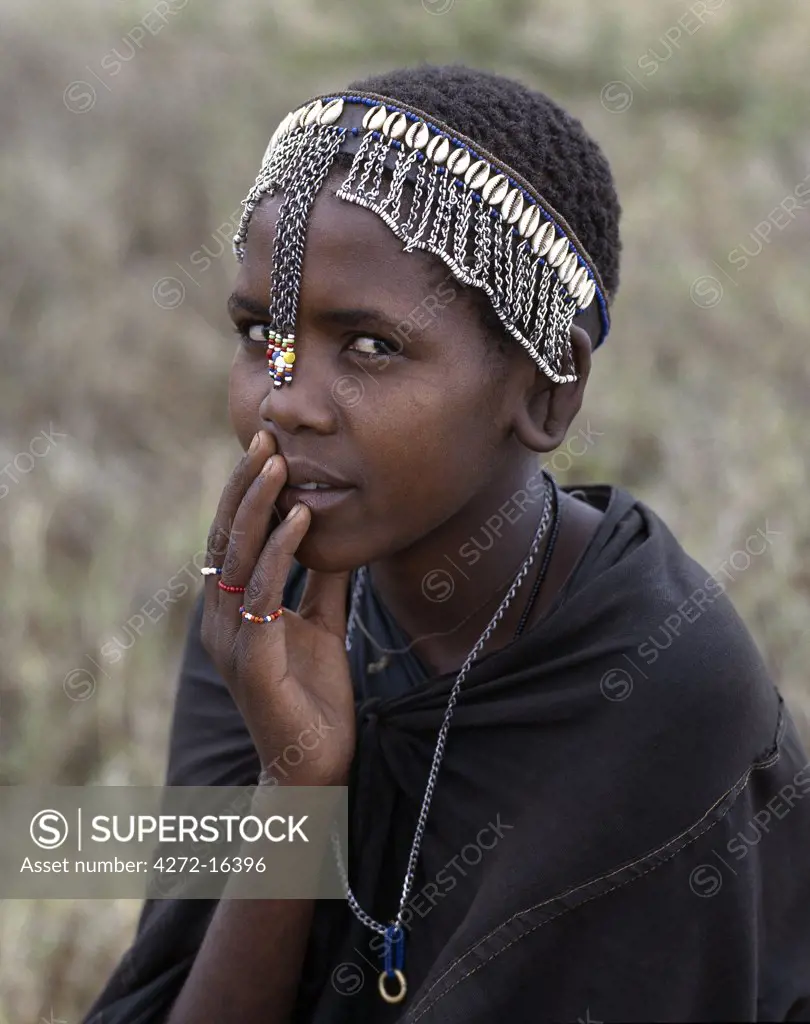 A young Maasai girl wears a headband decorated with chains and cowrie shells that signifies her recent circumcision. Clitodectomy was commonly practiced by the Maasai but it is now gradually dying out.