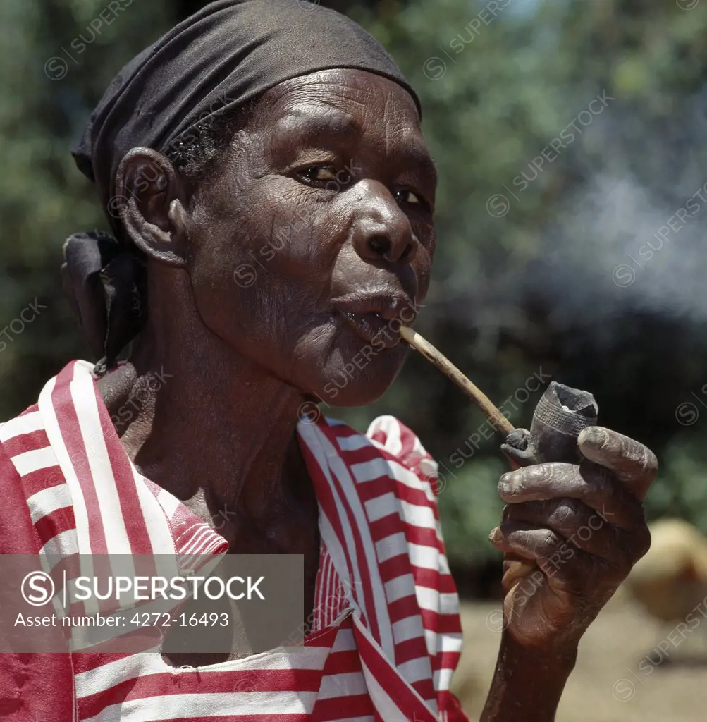 An old Luo lady smoking a traditional clay pipe.