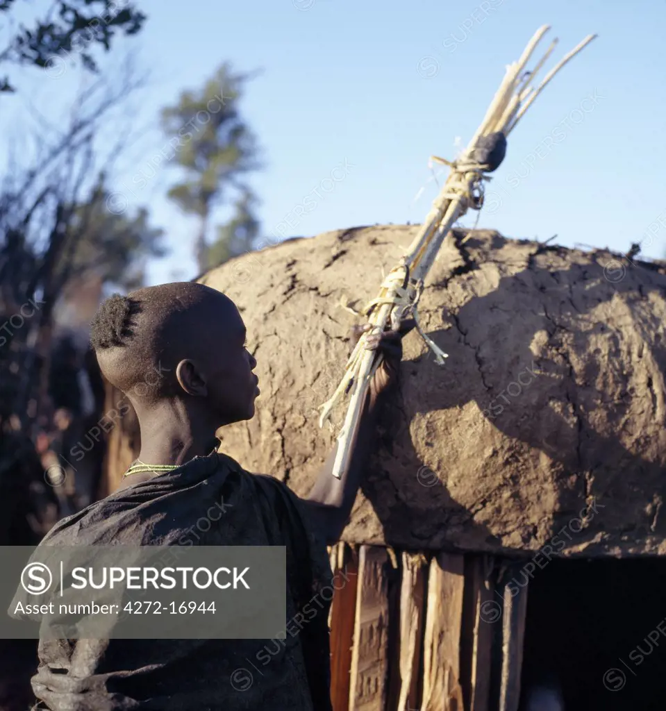 Dressed in black leather cloaks and singing the lebarta, Samburu boys return to their lorora in the early morning carrying over their right shoulders sticks, staves and gum, which they have collected to make bows, blunt arrows and clubs after their circumcision.