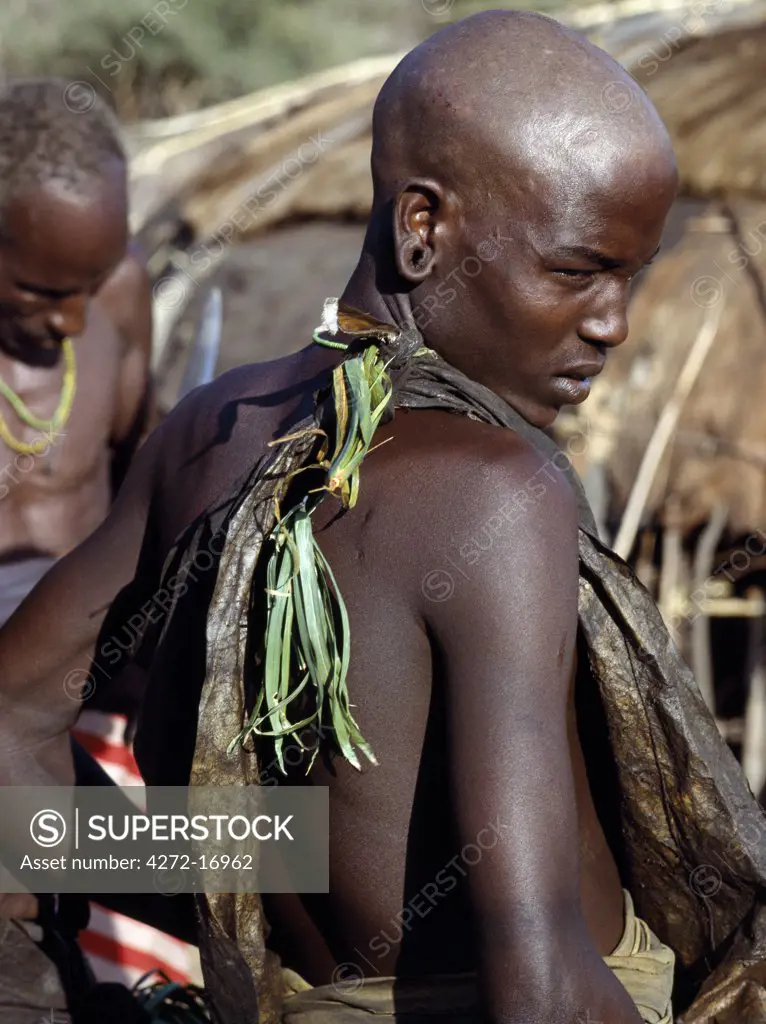 A Samburu youth in circumcision attire waits pensively for his turn 'under the knife'. The circumciser begins operating on the sons of the most senior family first and moves quickly in a clockwise direction Boys are not allowed to show any sign of fear or pain.  Even the blink of an eyelid is frowned upon.