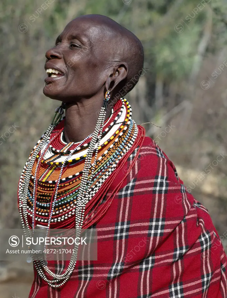 A Samburu woman singing.  The strings of black and white beads hanging from her ears signify that she has two grown-up sons who are warriors of the tribe. Note: the traditional horn snuff container hanging from her neck.