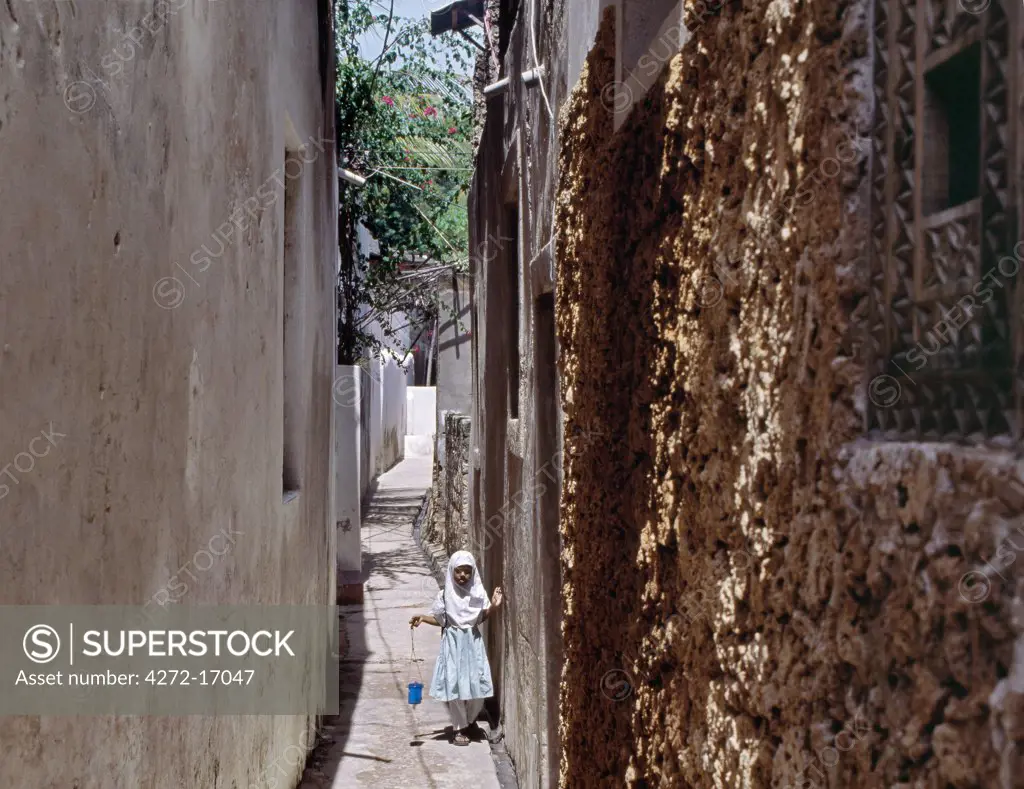 A young schoolgirl walks home along one of the narrow streets of Lamu town. Situated 150 miles north northeast of Mombasa, Lamu town dates from the 15th century AD.