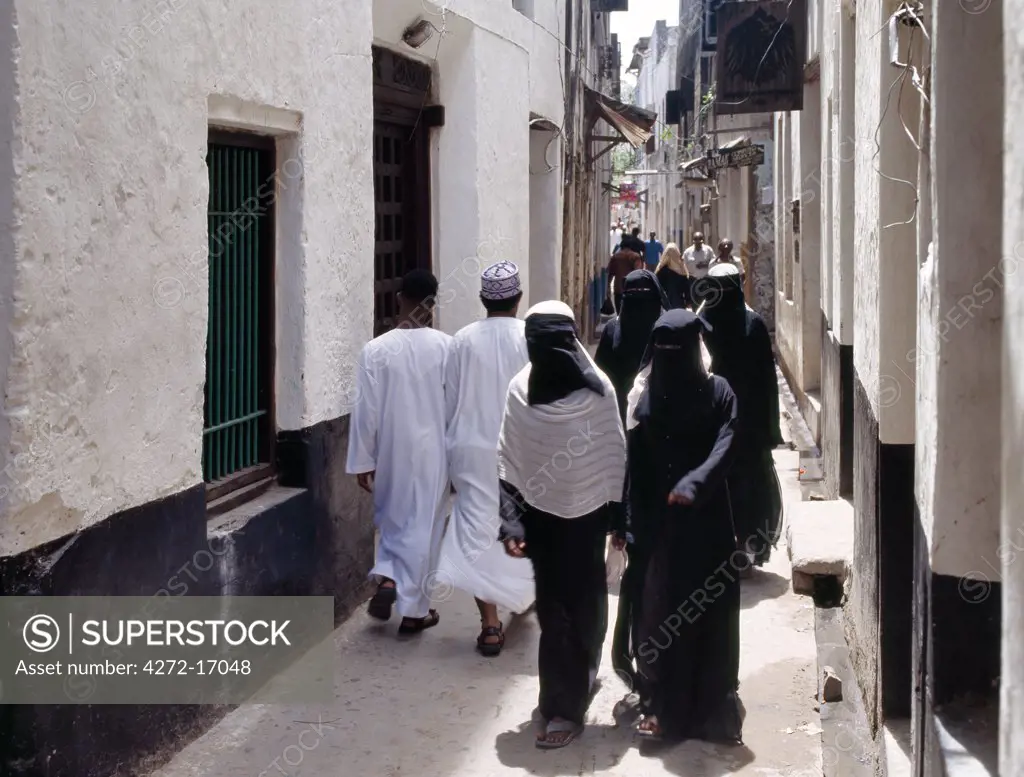 Muslim women with face veils walk along one of the many busy, narrow streets of Lamu town. Situated 150 miles north northeast of Mombasa, Lamu town dates from the 15th century AD.
