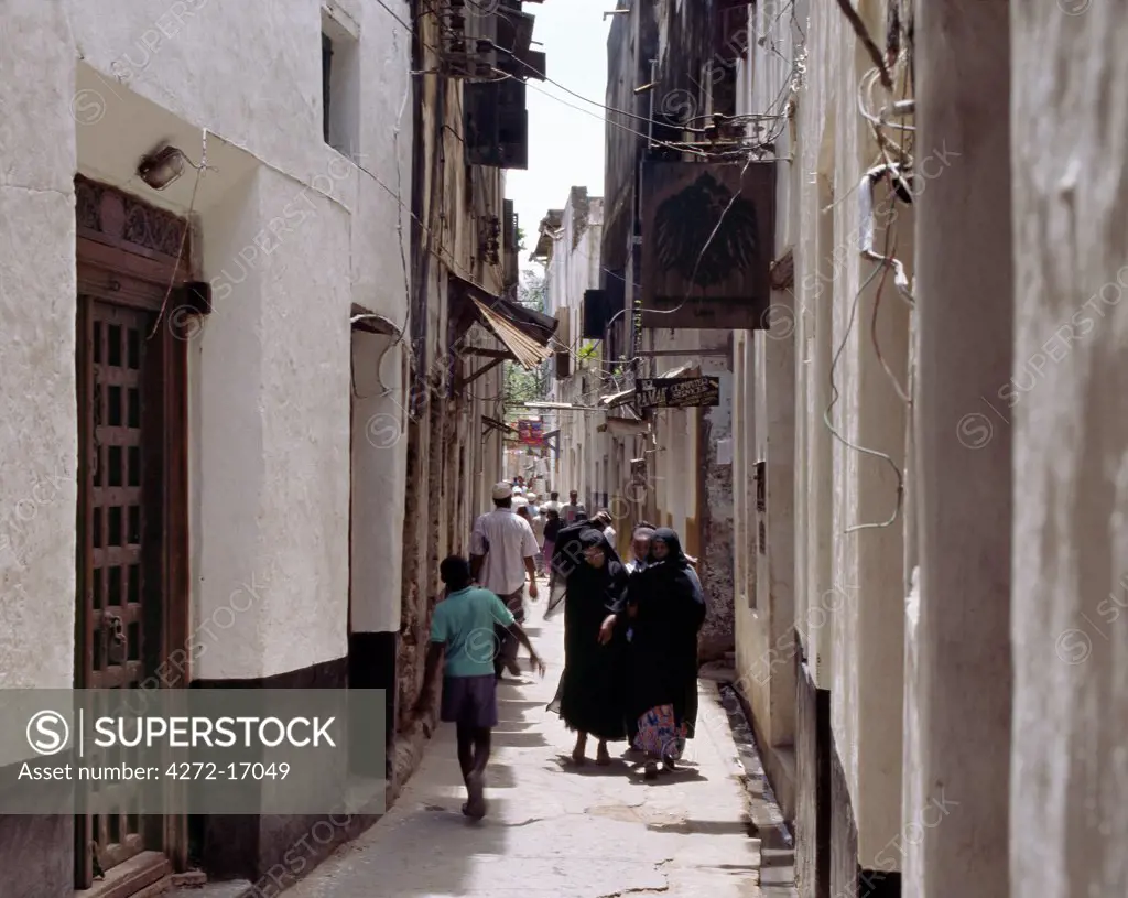 Muslim women with face veils walk along one of the many busy, narrow streets of Lamu town. Situated 150 miles north northeast of Mombasa, Lamu town dates from the 15th century AD.