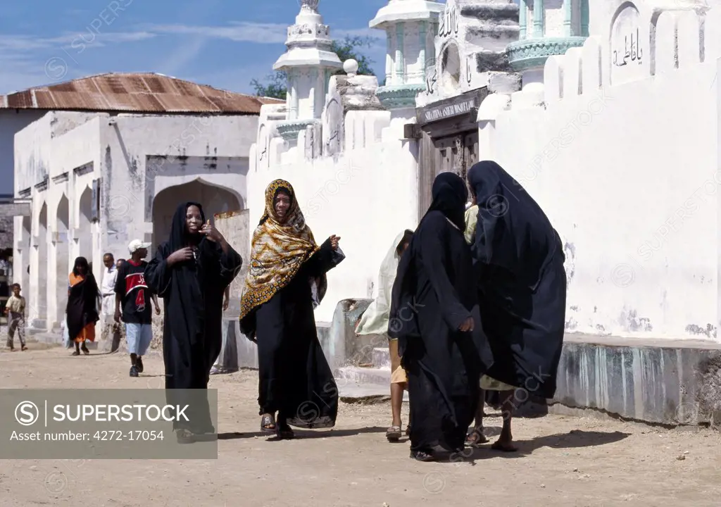 A group of Swahili women clad in black to signify their Islamic culture pause to chat outside an old mosque along the waterfront of Lamu Island. The majority of people on the island practice a fairly relaxed form of Islam. Situated 150 miles north northeast of Mombasa, Lamu town dates from the 15th century AD.