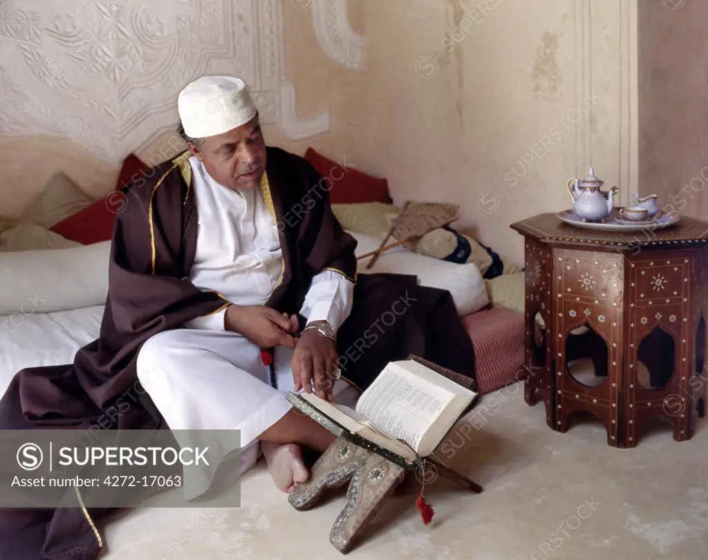 Abdul Malik Bilali recites the Holy Koran in his beautiful stone built house in Lamus old town. The house has fine example of decorative Lamu plasterwork gracing the interior walls. The extraordinary skill of the local craftsmen is an important legacy of Afro Arab architecture in the Swahili style.  local Swahili style and culture.