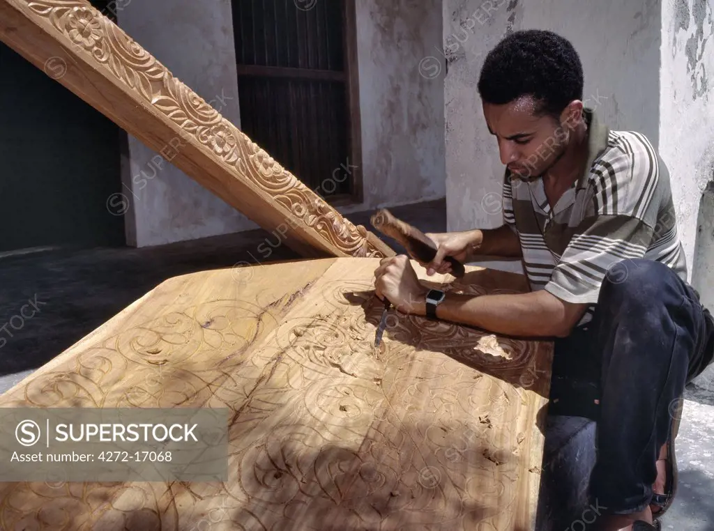 A skilled craftsman with traditional tools carves a wooden door from hardwood in Lamu town.  Wood carving is the most important craft in Lamu and sustains the greatest number of skilled craftsmen. Situated 150 miles north northeast of Mombasa, Lamu town dates from the 15th century AD.