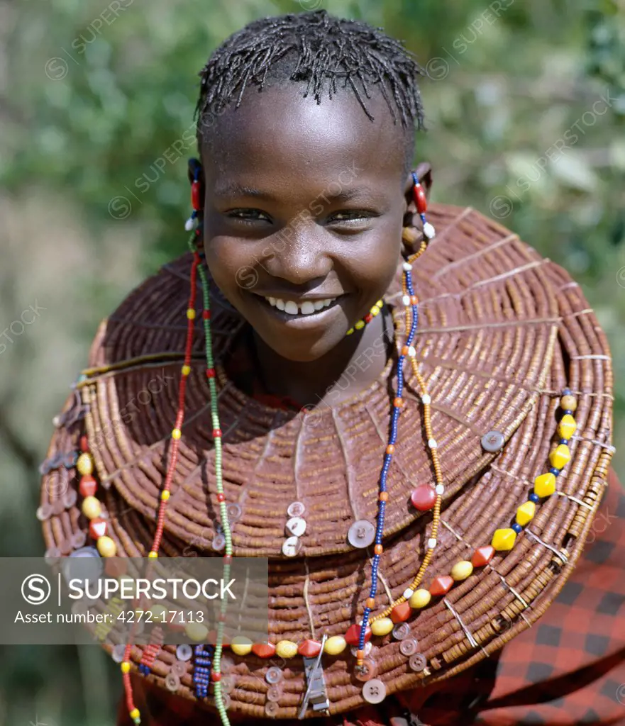 A young Pokot girl wears large necklaces made from the stems of sedge grass, which are then plastered with a mixture of animal fat and red ochre before being decorated with buttons and beads.