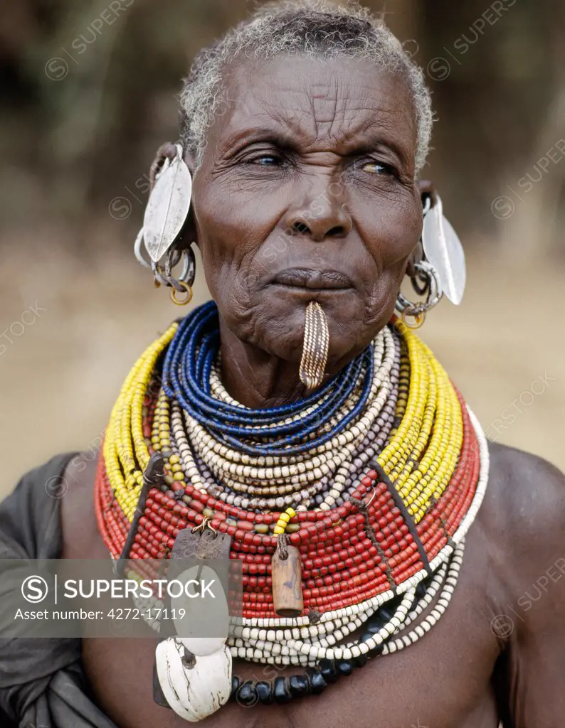 An old Turkana woman wearing all the finery of her tribe. In a hole pierced below her lower lip, she wears an ornament beautifully made from twisted strands of copper wire.