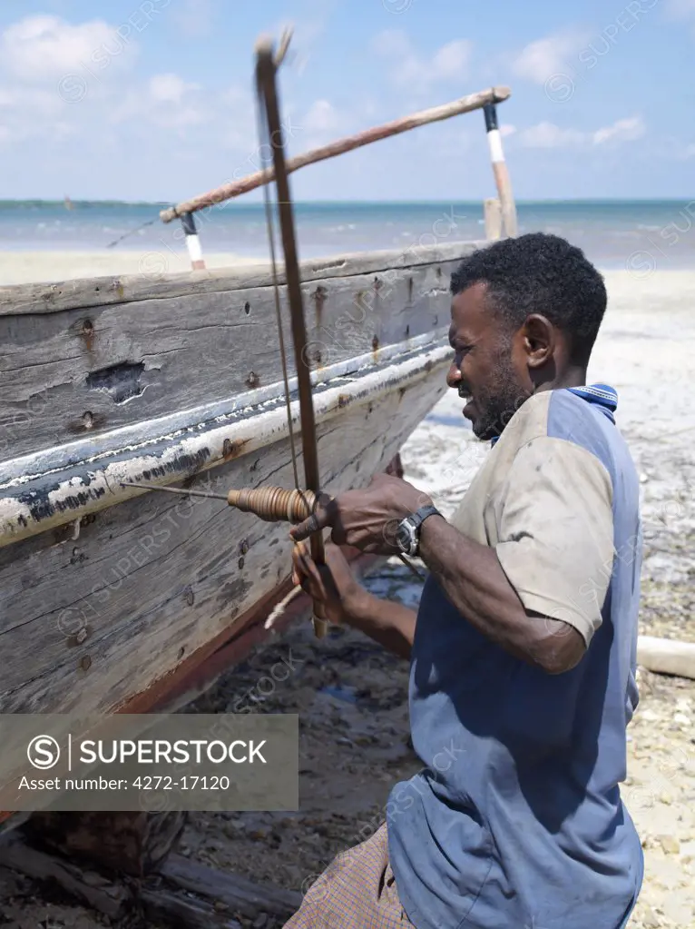 A shipwright drills a hole to repair a wooden sailing boat, known as mashua, at Kisingitini, a natural harbour on Pate Island.  The centuries old technology of the bow drill he uses is ideal for places where there is no electricity. The island is the largest of the Lamu Archipelago lying in the Indian Ocean.