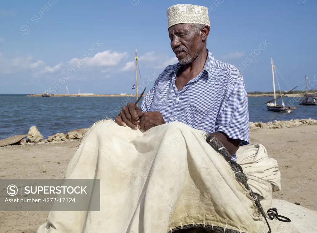 A fisherman repairs the sail of his wooden sailing boat, known as mashua, along the waterfront of Kisingitini, a natural harbour on Pate Island. The island is the largest of the Lamu Archipelago lying in the Indian Ocean.