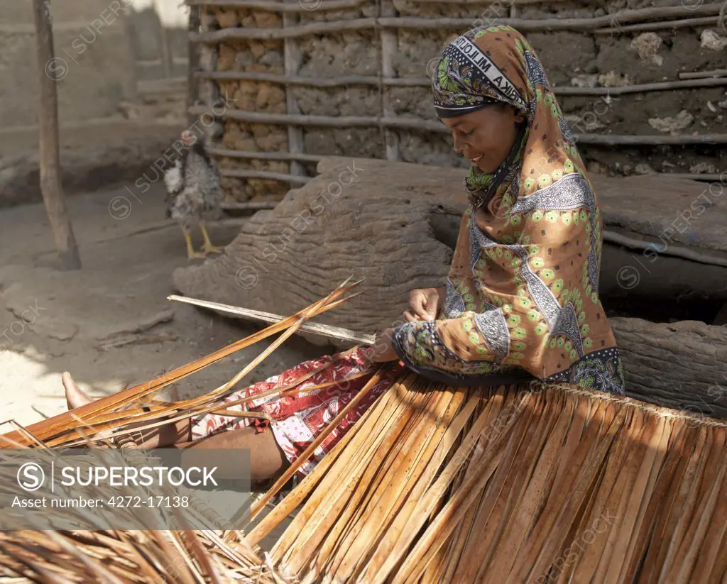 A woman makes makuti, a thatch from dried fronds of coconut palms, outside her home in Faza village.  The chequered history of Faza dates back several hundred years.  It was destroyed by Pate in the 13th century and again by the Portuguese in 1586.
