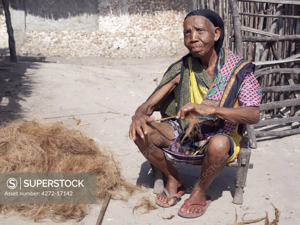 Seated on a wooden stool outside her home in Faza village, an old Swahili woman makes twine out of the coir of rotted coconut husks.  She does this by rolling the fibre up and down her thigh.  The twine is highly resistant to salt water and is used for rigging in preference to nylon. The chequered history of Faza dates back several hundred years.