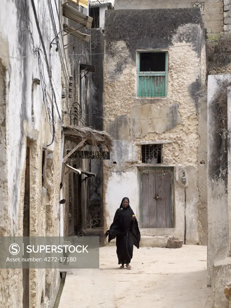 A Swahili woman dressed in black to signify her Muslim faith walks through the narrow streets of Lamu town.  Situated 150 miles north northeast of Mombasa, Lamu town dates from the 15th century AD.