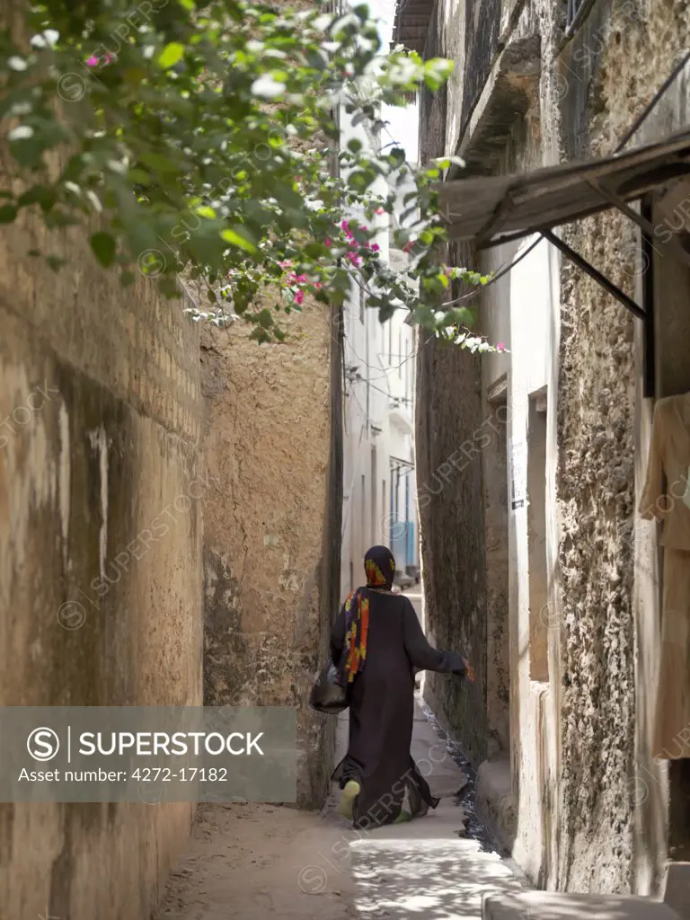 A Swahili woman dressed in black to signify her Muslim faith walks through the narrow streets of Lamu town.  Situated 150 miles north northeast of Mombasa, Lamu town dates from the 15th century AD.