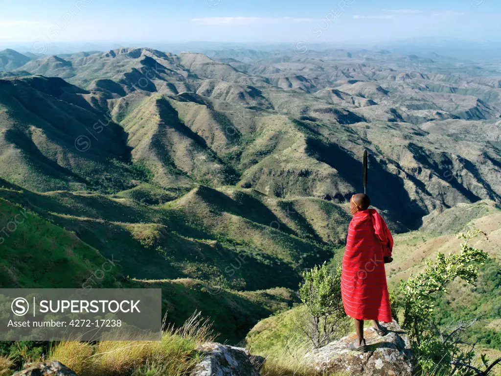 A magnificent view from the eastern scarp of Africa's Great Rift Valley at Losiolo, north of Maralal.  From 8,000 feet the land tumbles away 3,000 feet into rugged valleys and a broad plain, the domain of nomadic pastoralists, before rising again 75 miles away.  The views at Losiolo are the finest in Kenya of the largest, longest and most conspicuous physical feature of its kind on earth.  A Samburu warrior looks out over the vast expanse.