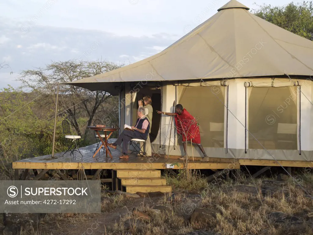 A Maasai guide points out a wild animal to visitors on the verandah of their comfortable tent at Ol Seki Tented Camp in Masai Mara Game Reserve.