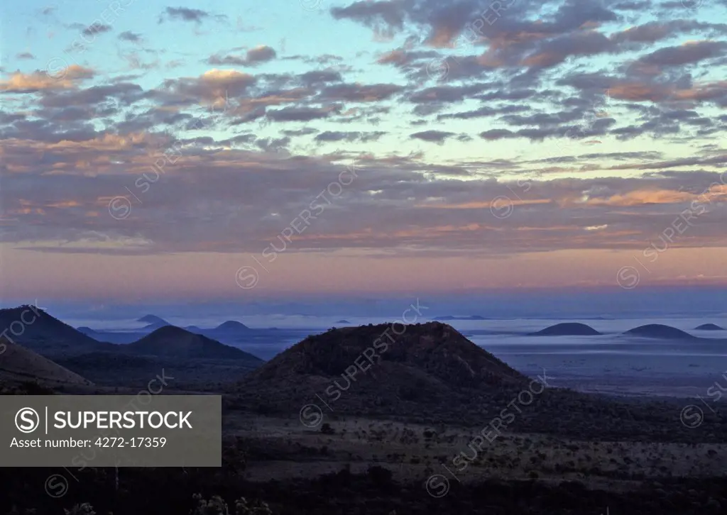 Dawn sky with low clouds surrounding volcanic cones near the Chyulu Hills.