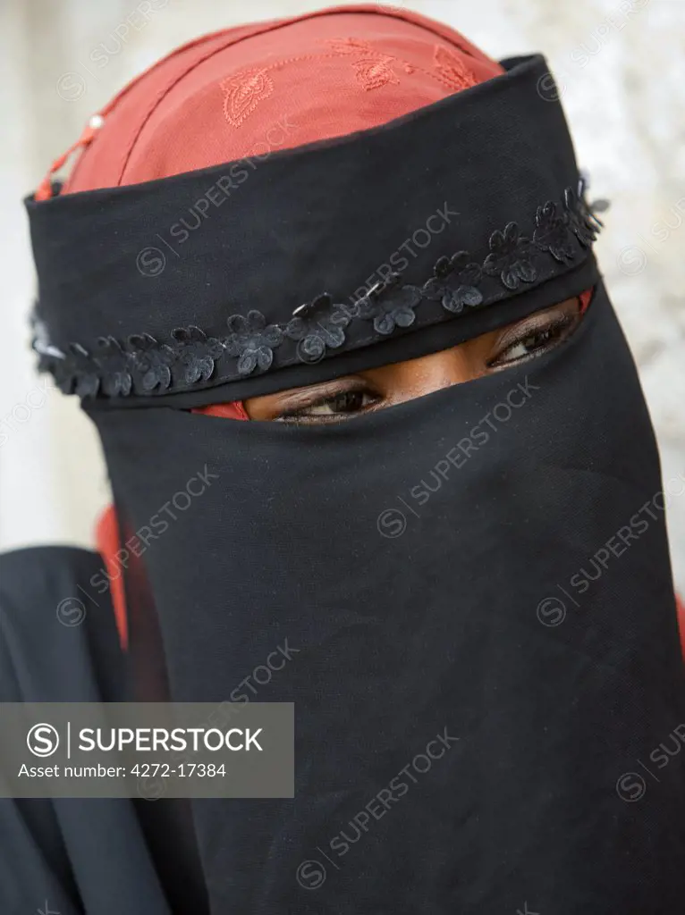 Kenya, Lamu Island, Lamu. A Muslim woman of Lamu town elegantly dressed in a buibui or face veil.