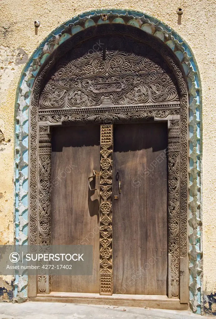 Kenya, Lamu Island, Lamu. A beautifully carved old wooden door in Lamu town. Lamu craftsmen are renowned for their carved doors.