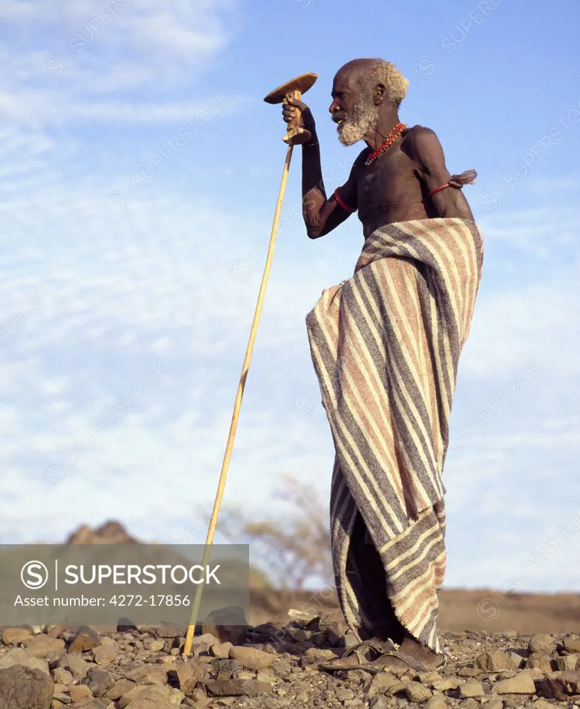 Kenya, Turkana District. An old Turkana man holding his carved wooden stool cum headrest in his right hand.