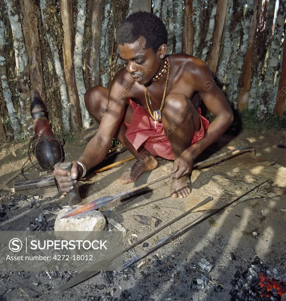 A Samburu blacksmith fashions the head of a spear in his workshop.