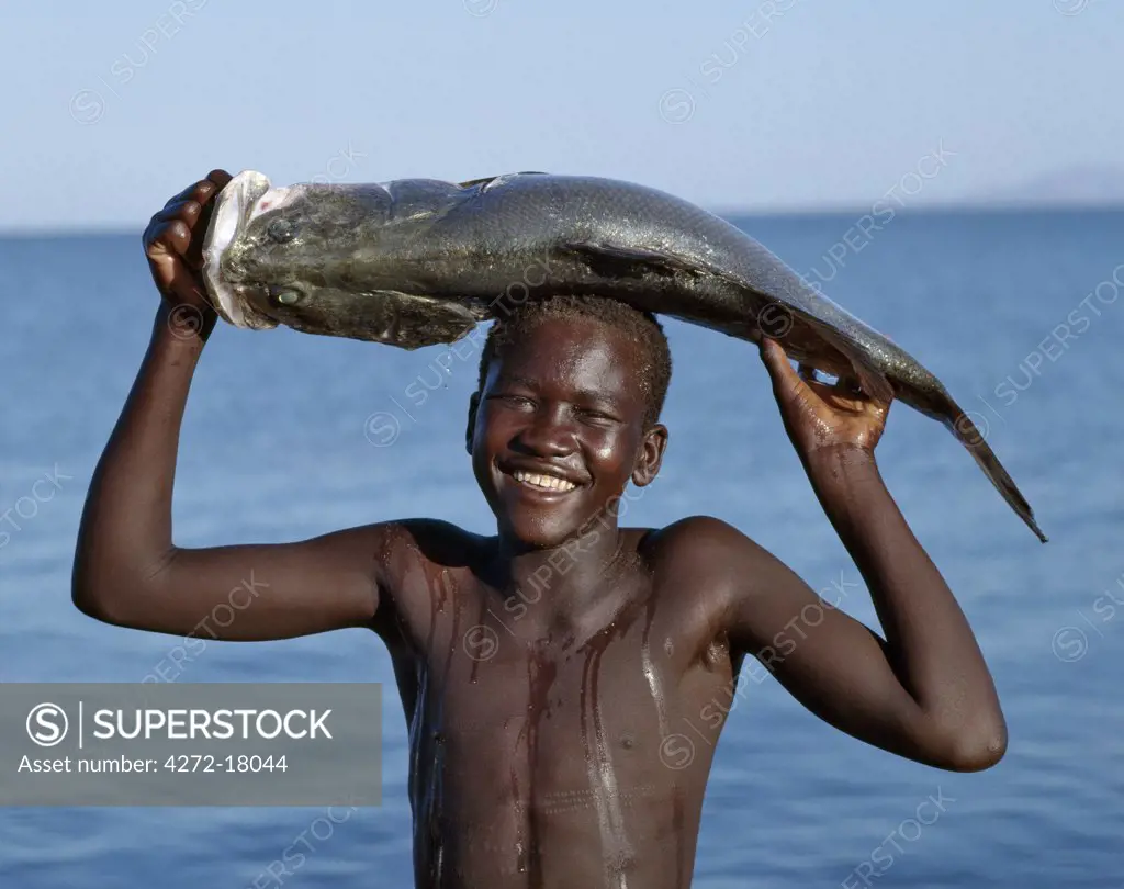 A happy Turkana boy carries home a Nile perch which he caught in Lake Turkana.