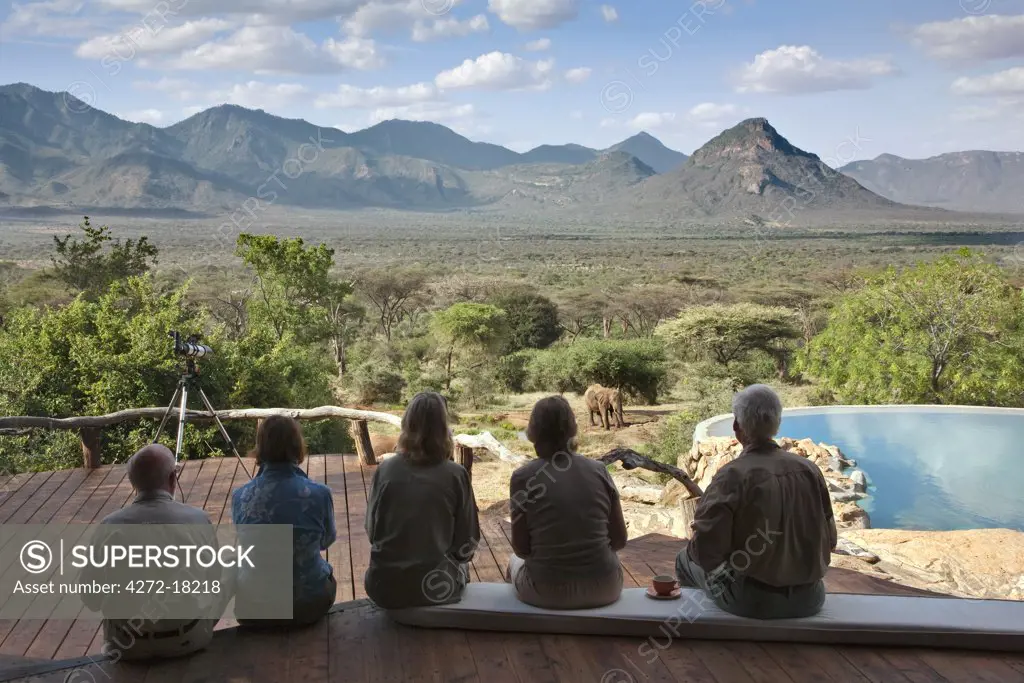 Kenya, Guests at Sarara Camp, an ecolodge situated near the Mathews Mountains, watch an elephant drink at the nearby waterhole.