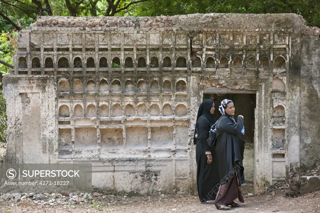 Kenya, Muslim women from Lamu pause beside the ruins of a once-imposing C19th residence near the Wa Deule Mosque at Shela.