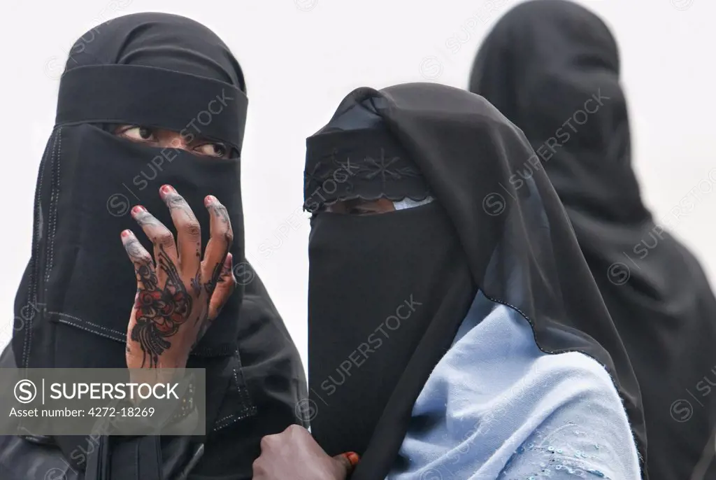 Kenya. Lamu women in fashionable Muslim dress. One lady has traditional henna hand designs