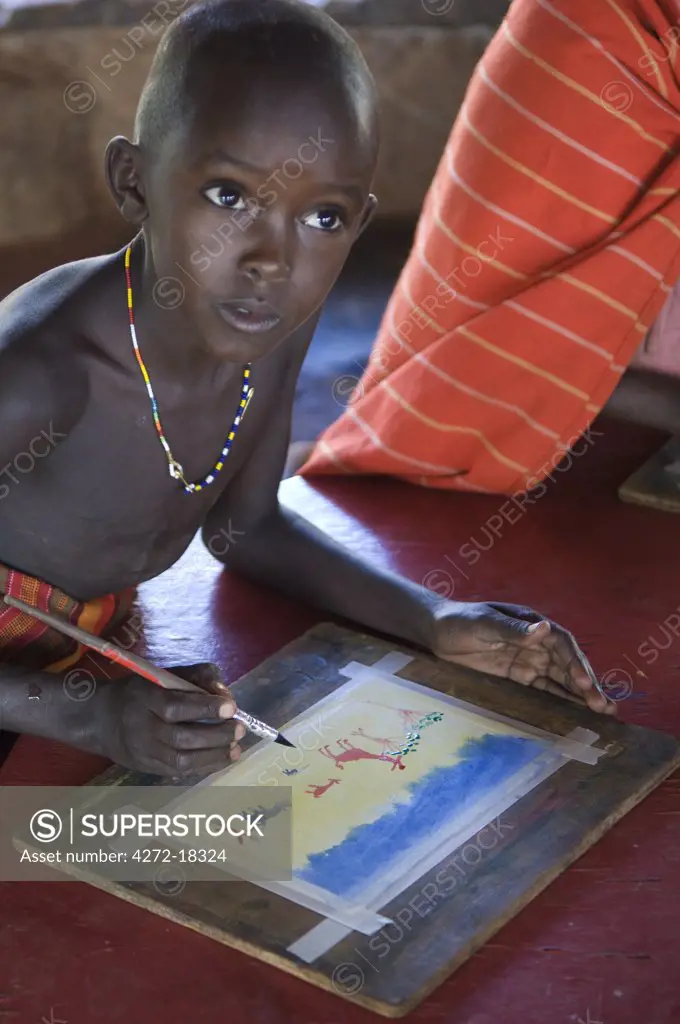 Kenya, Laikipia, Ol Malo.  Pires Tiresi Lochopoko, a 10 year old Samburu boy painting at the Sampiripiri Art Project.