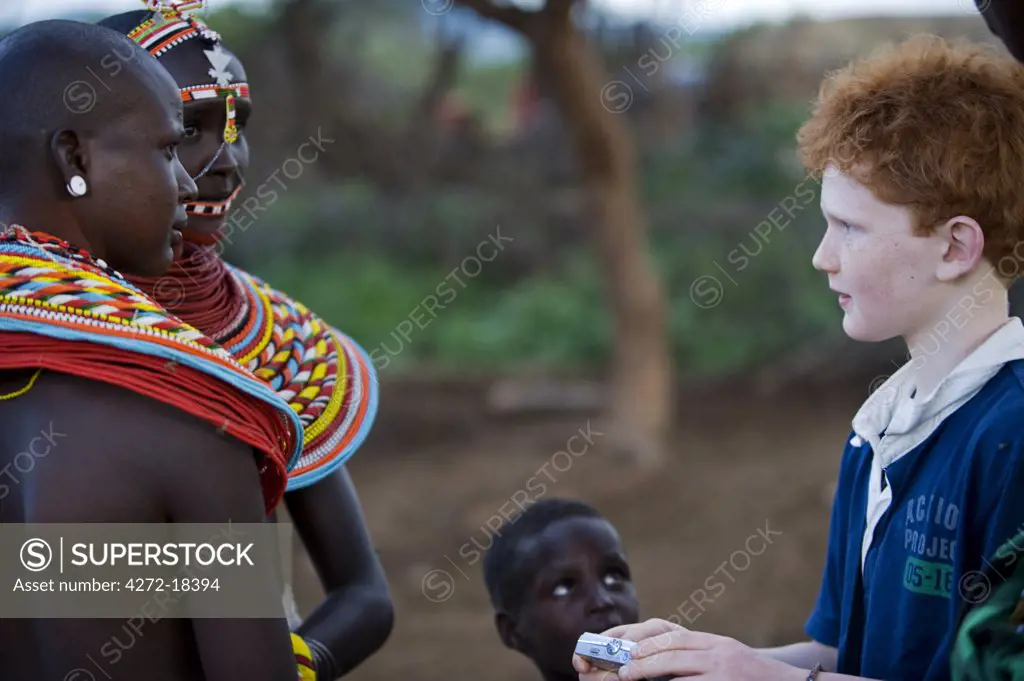 Kenya, Laikipia, Ol Malo.  A young visitor on safari at Ol Malo meets local Samburu at a manyatta.