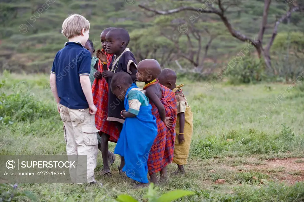 Kenya, Laikipia, Ol Malo.  A young visitor on safari at Ol Malo meets local Samburu children at a manyatta.