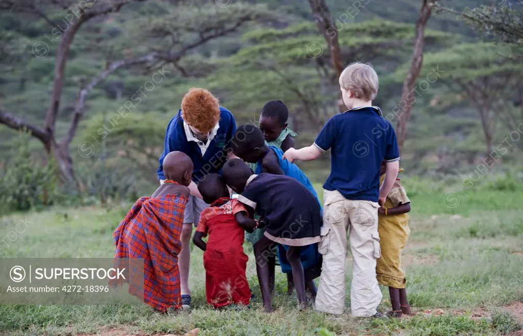 Kenya, Laikipia, Ol Malo.  Young visitors on safari at Ol Malo meet local Samburu at a manyatta.