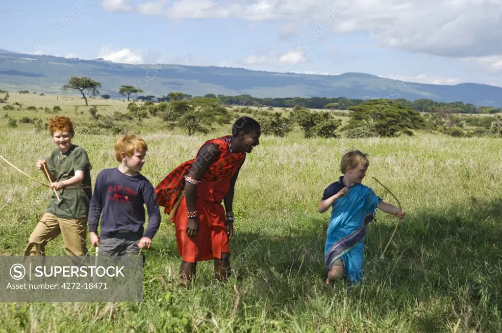 Kenya, Laikipia, Lewa Downs. Children on a family safari practise archery with one of the Maasai guides. (MR)