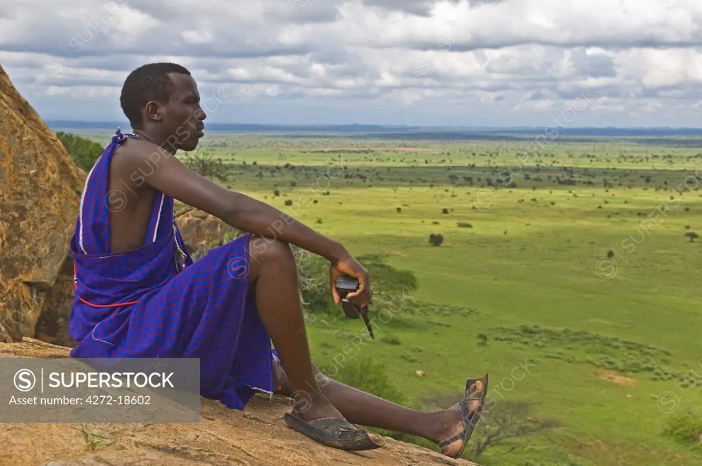 Kenya, Chyulu Hills, Ol Donyo Wuas.  Safari guide, Daniel Kasaine, looks out over the plains from a rock kopje.  (MR)