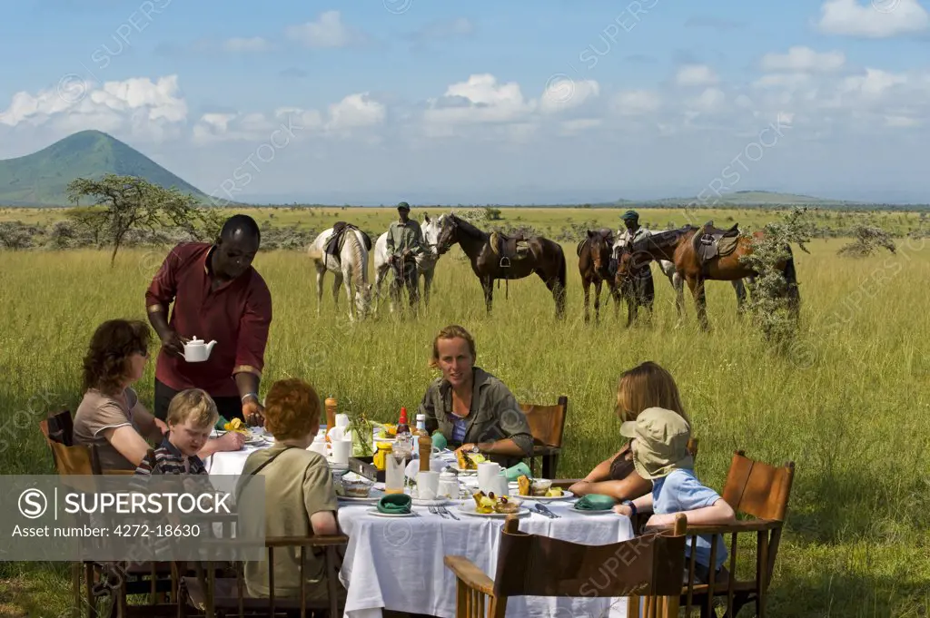 Kenya, Chyulu Hills, Ol Donyo Wuas.  Family on a riding safari enjoy their bush breakfast.