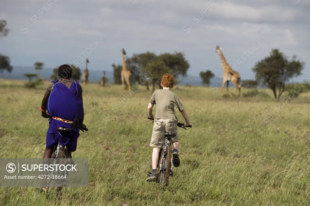 Kenya, Chyulu Hills, Ol Donyo Wuas. A Maasai guide and boy on a mountain biking safari towards Maasai giraffe. (MR)