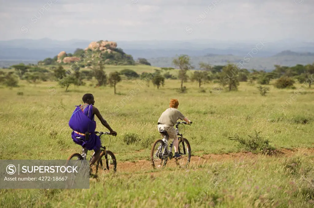 Kenya, Chyulu Hills, Ol Donyo Wuas. A Maasai guide and boy on a mountain biking safari. (MR)