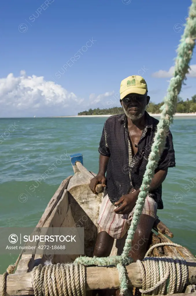 Kenya, Coast, Diani Beach.  Fisherman at the tiller of his ngalawa or outrigger sailing canoe.