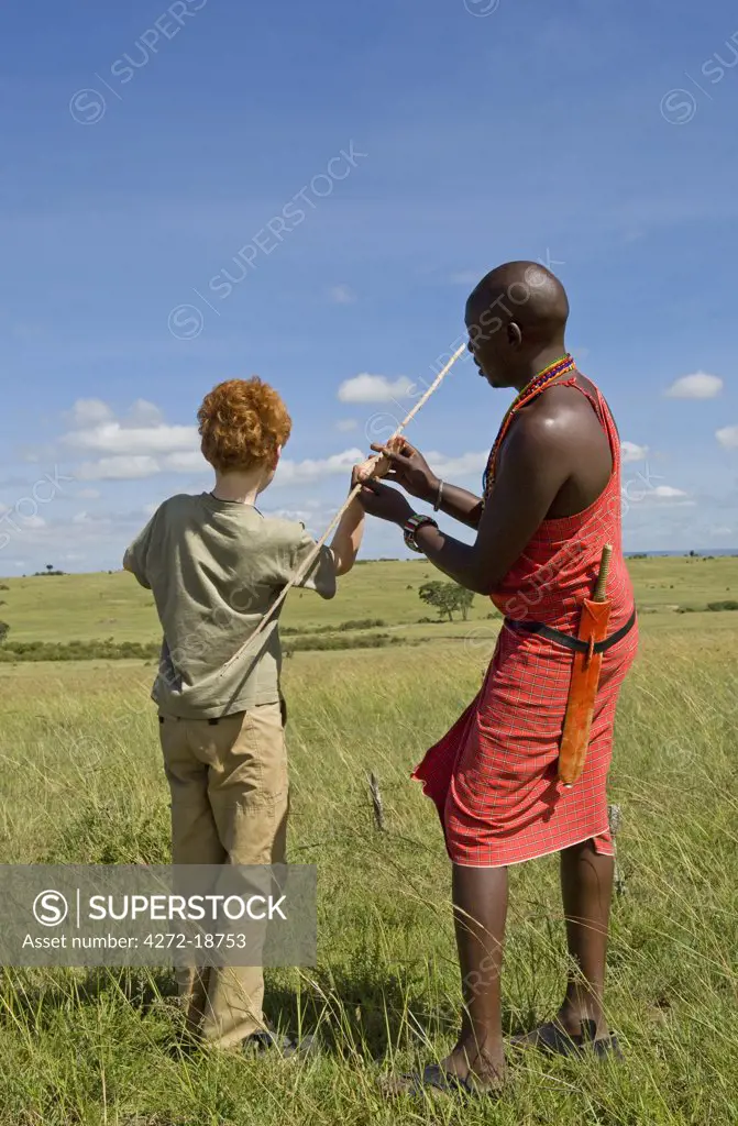 Kenya, Masai Mara.  Safari guide, Salaash Ole Morompi, shows young boys on safari how to throw a spear. (MR)