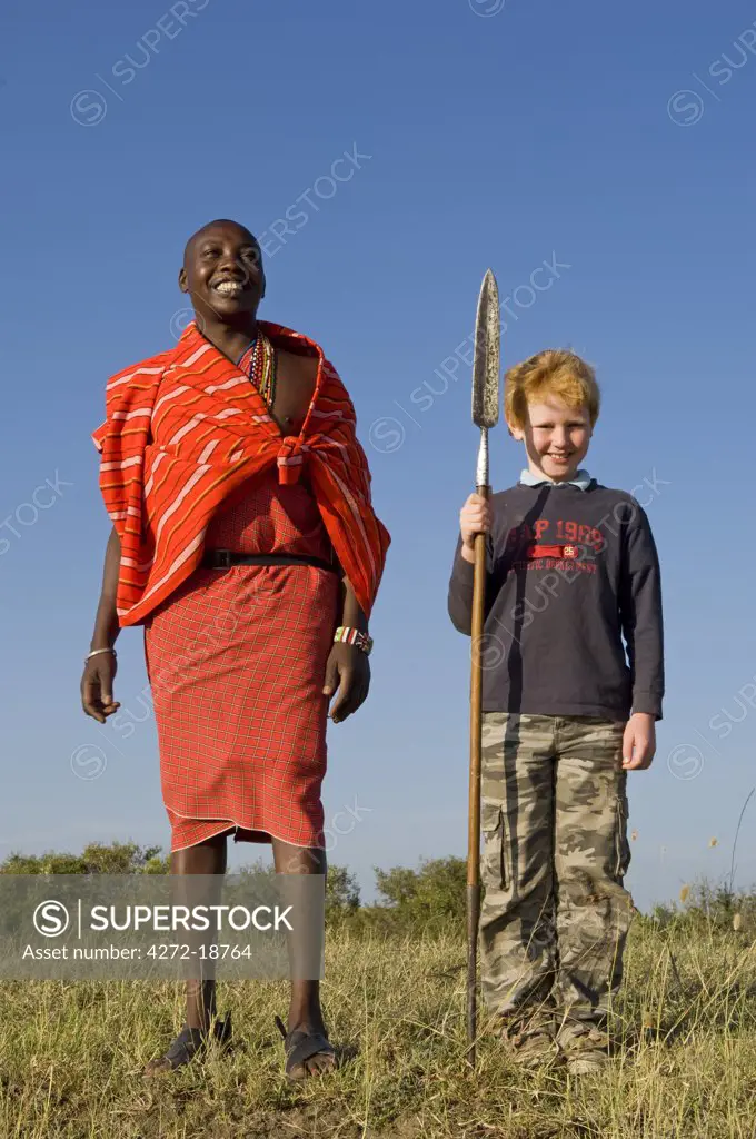 Kenya, Masai Mara.  Safari guide, Salaash Ole Morompi, with a young boy on a family safari. (MR)